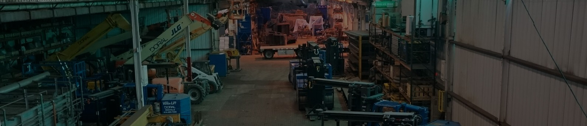 An industrial warehouse filled with equipment and machinery, including forklifts, cranes, and various tools, organized along the aisles for operations and manufacturing tasks.